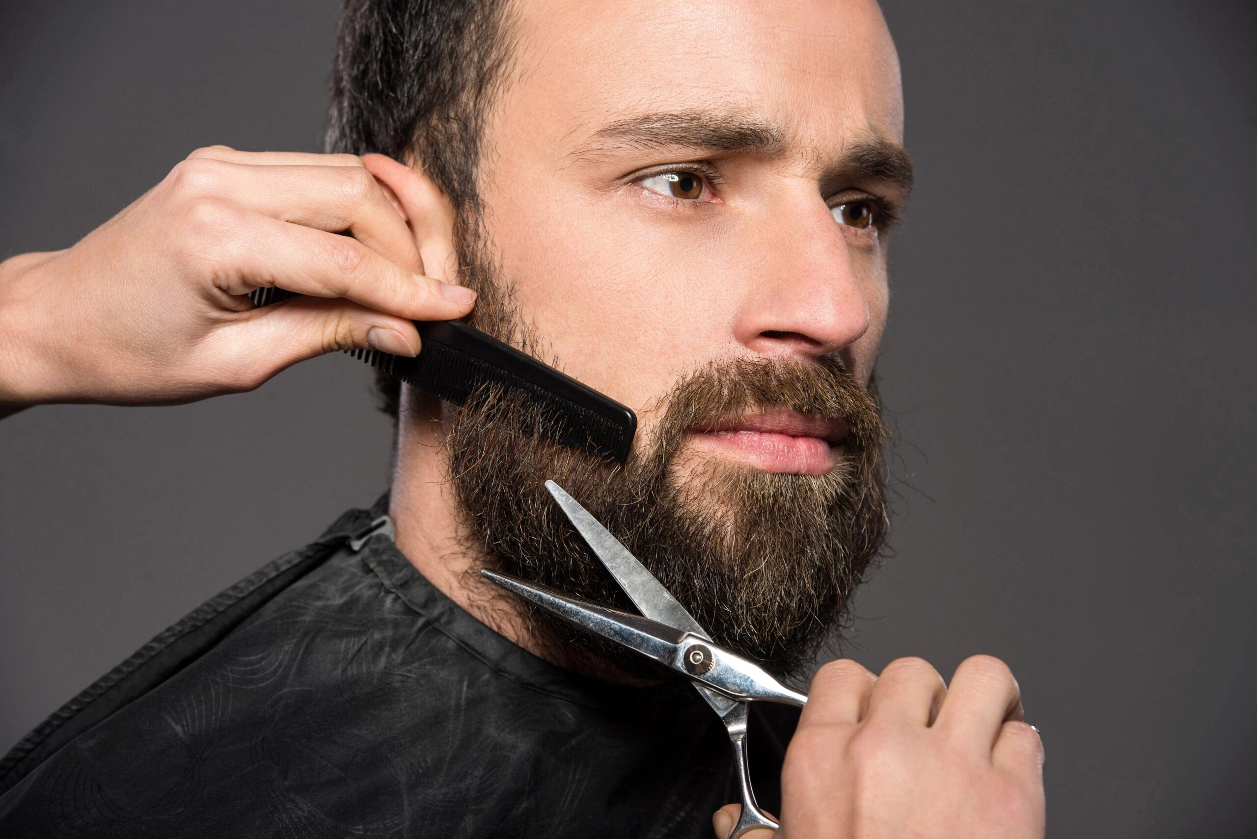 Portrait of man having his beard trimmed